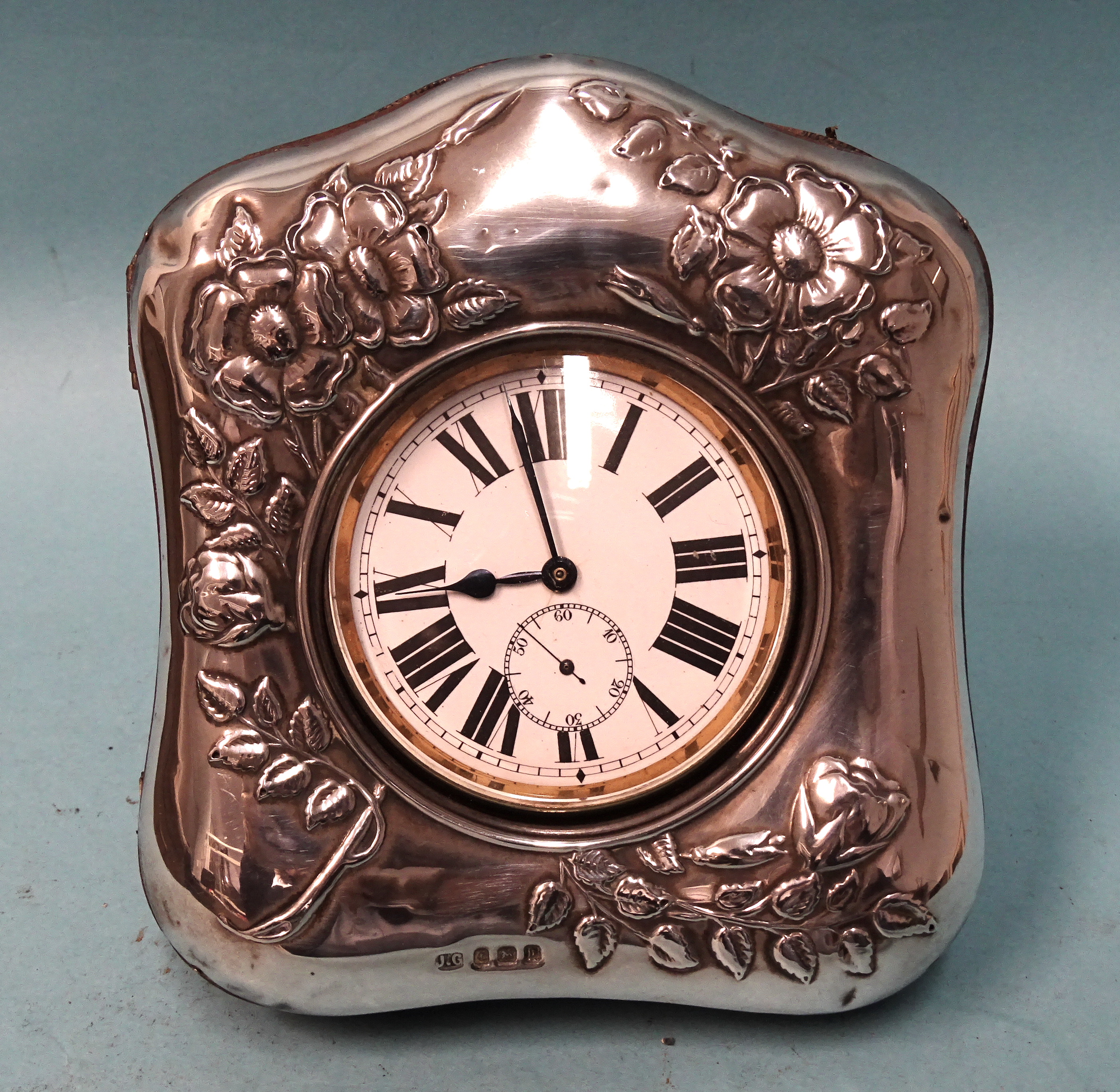 A silver watch holder of arched form with embossed floral decoration, 12.5 x 11.5cm, Birmingham