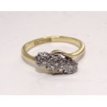 A three-stone diamond ring, the brilliant-cut diamonds illusion-set in 18ct gold and platinum mount,