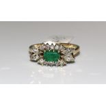An emerald and diamond cluster ring claw-set a rectangular emerald between two lines of five