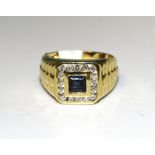 A sapphire and diamond cluster ring set a square-cut sapphire within a border of sixteen channel-set