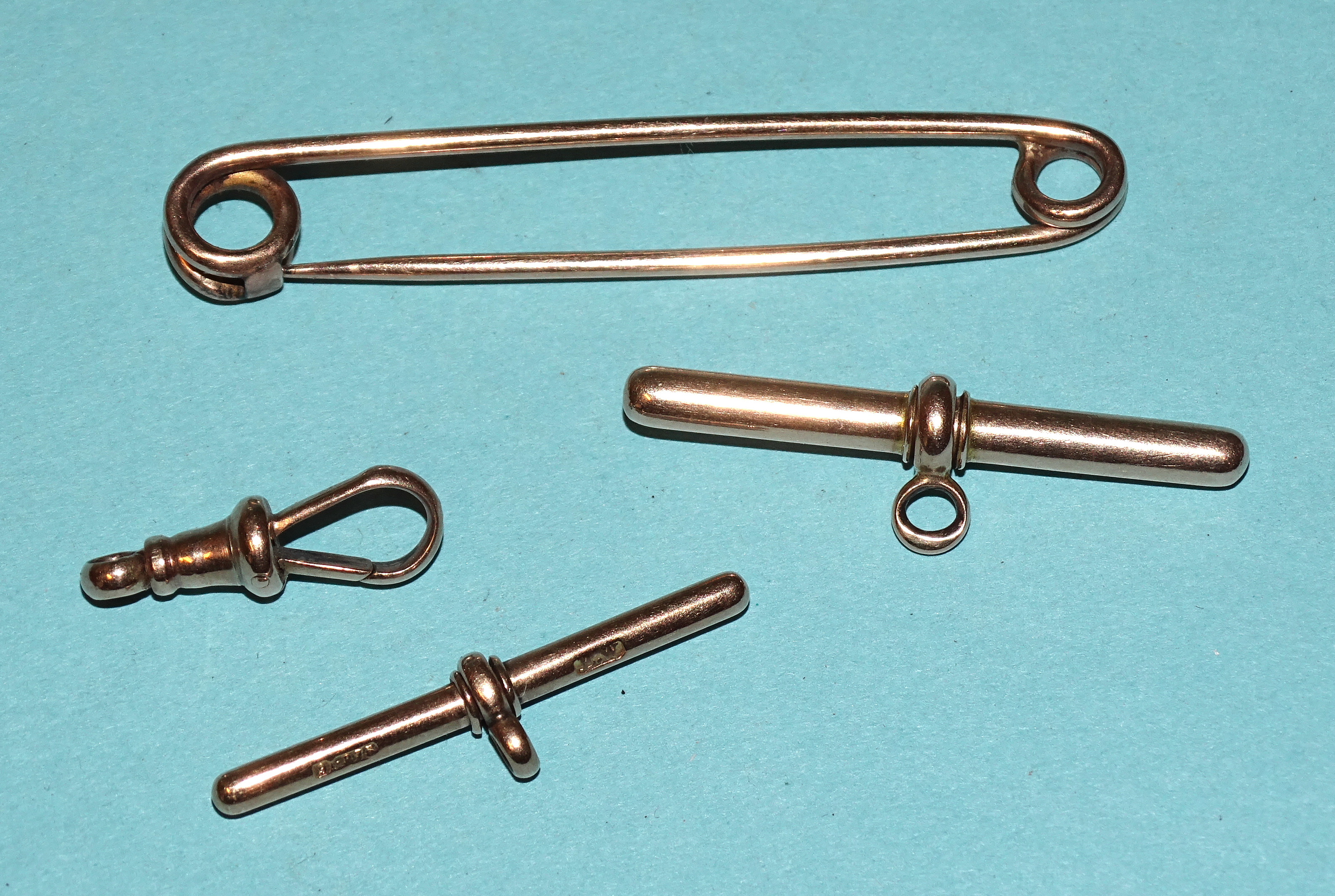 A 9ct gold T-bar, another, unmarked and a shackle, 7.2g, with a gold-plated stock pin.