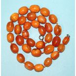 A string of thirty-three butterscotch amber beads, of roughly the same size, 23 x 18mm, 81cm long,