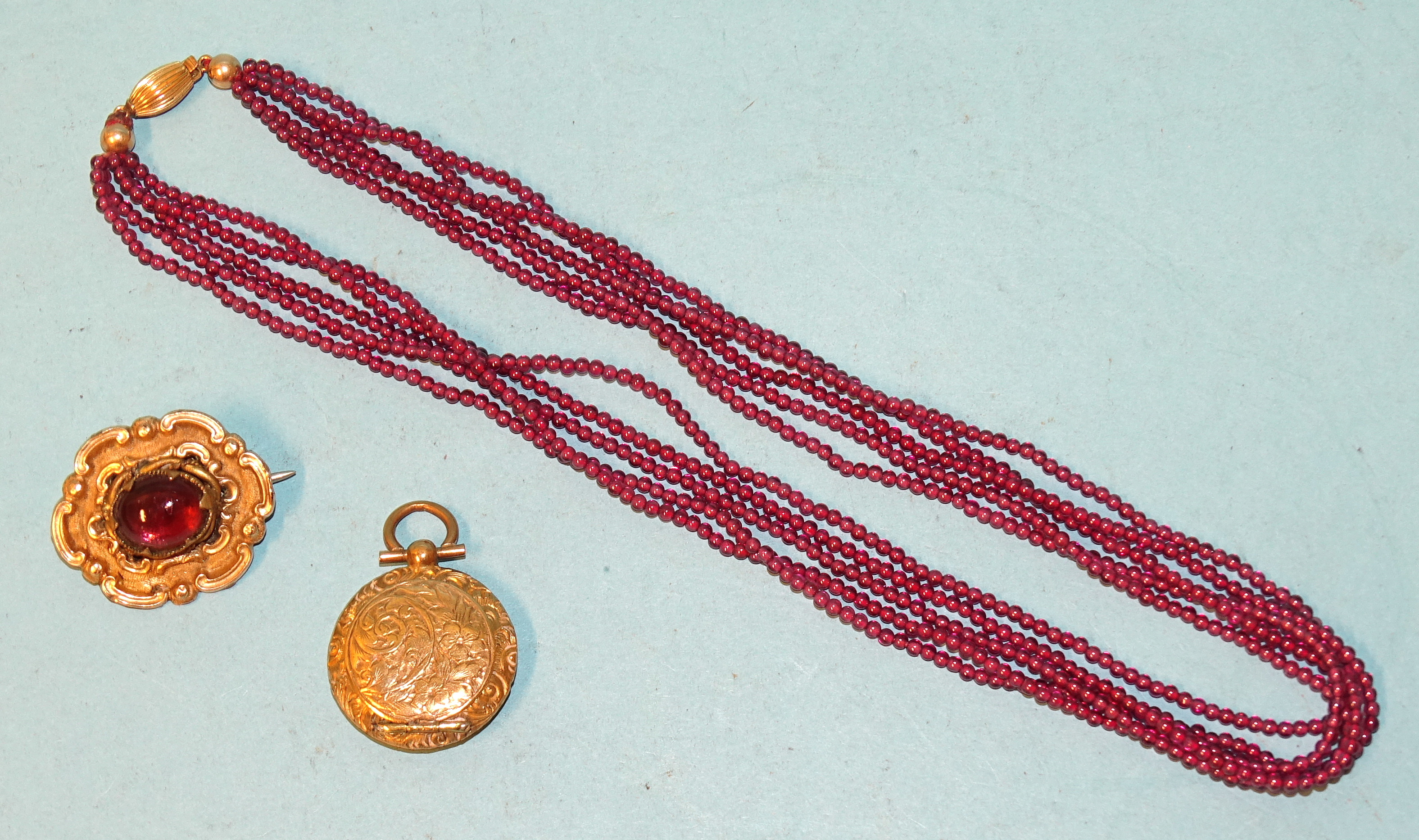 A 19th century mourning brooch with later paste cabochon, a gilt metal locket and a necklace of five