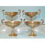 A set of four small circular silver sweetmeat dishes with scroll handles, raised on tapering