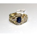 A sapphire and diamond cluster ring claw-set a step-cut sapphire amid three wavy lines of channel-