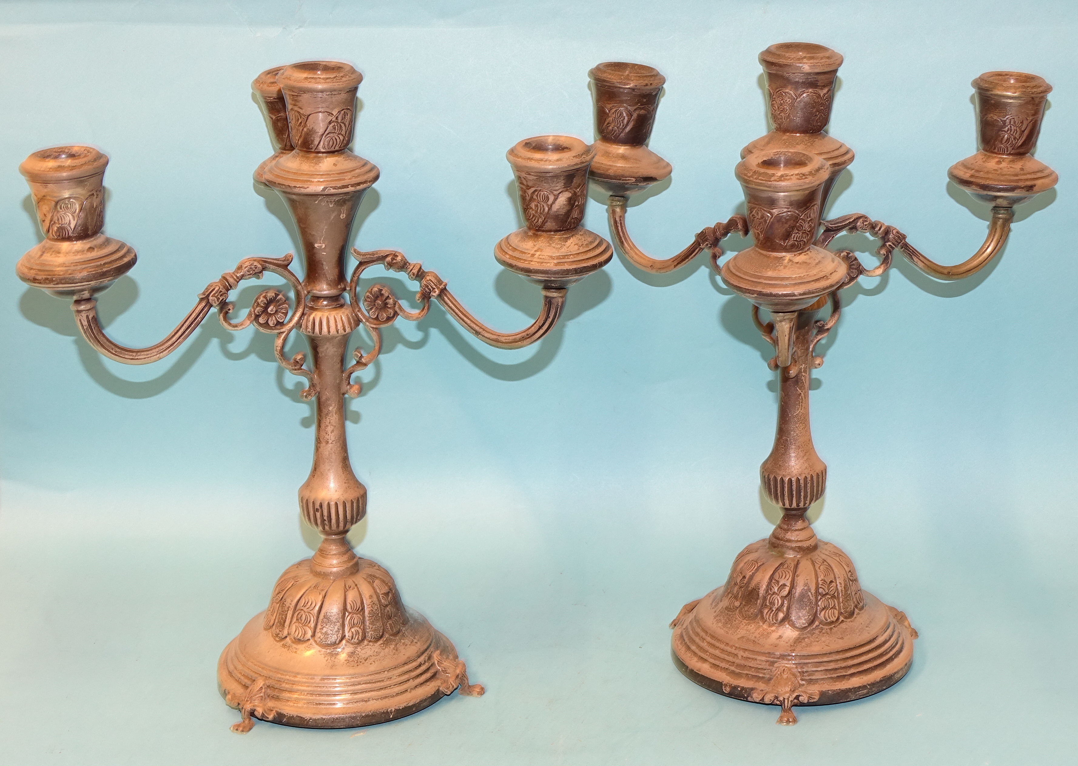 A pair of Egyptian silver three-branch candelabra with baluster stems and domed bases, on three claw