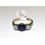 A sapphire and diamond ring claw-set a round-cut sapphire between two brilliant-cut diamonds, in