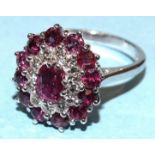 A ruby and diamond cluster ring claw-set an oval ruby within concentric borders of twelve each