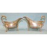 Two silver sauce boats of bellied form, (one slightly smaller than the other), with cast rims and