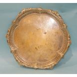A silver salver with cast six-lobed rim and engraved decoration, raised on three claw and ball feet,
