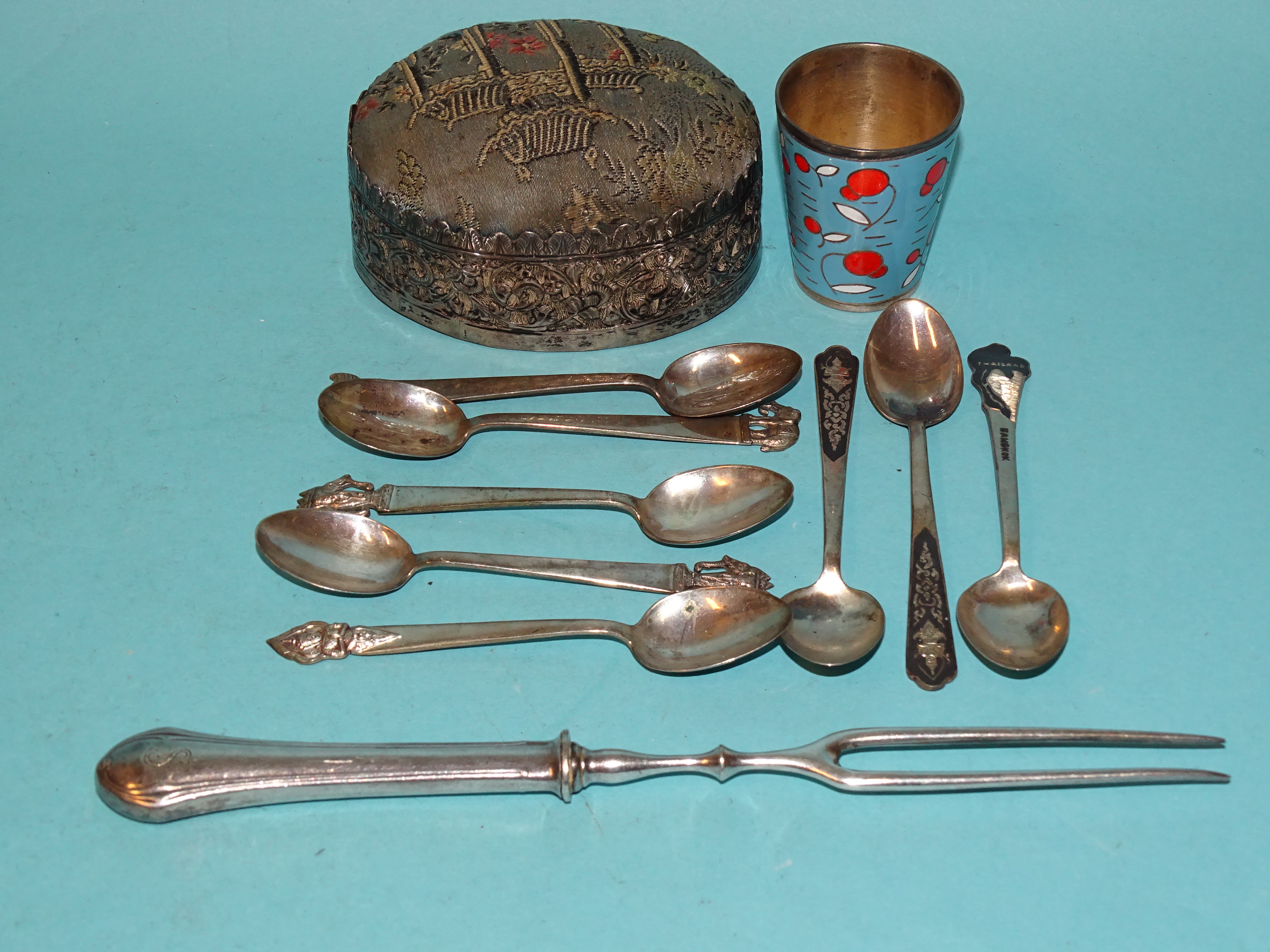 A large white metal-sided pin cushion, an enamelled tot beaker, eight coffee spoons marked '