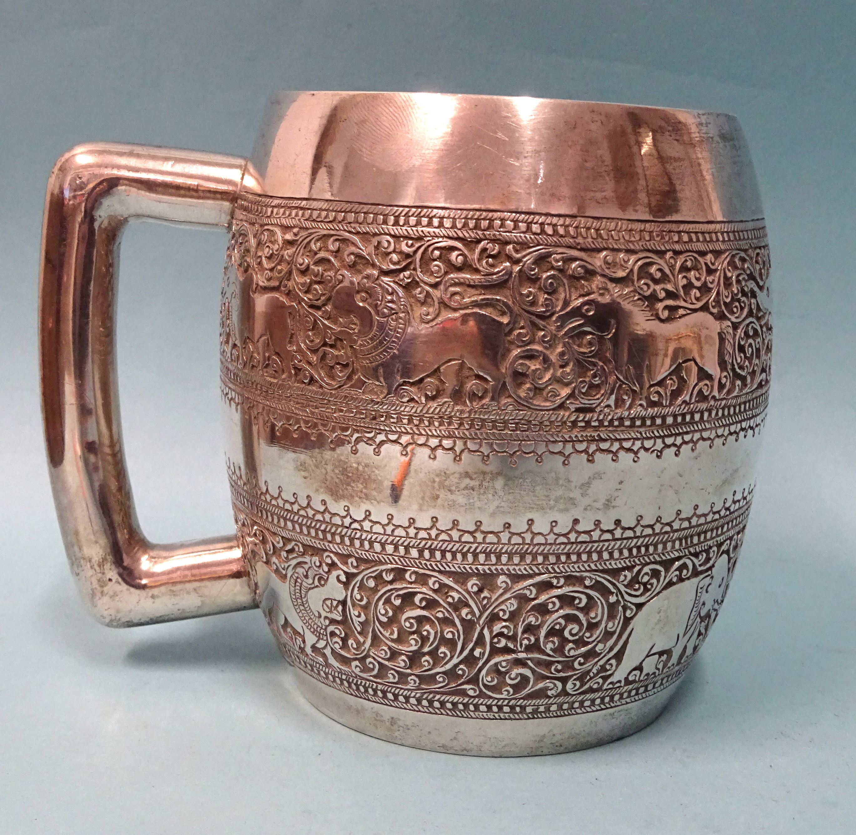 A South Asian Ceylonese silver tankard decorated with two bands of wild animals amid scroll work,