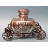 A silver inkwell of Baroque form, raised on ornate carriage with four wheels, 9cm high, 12.5cm long,