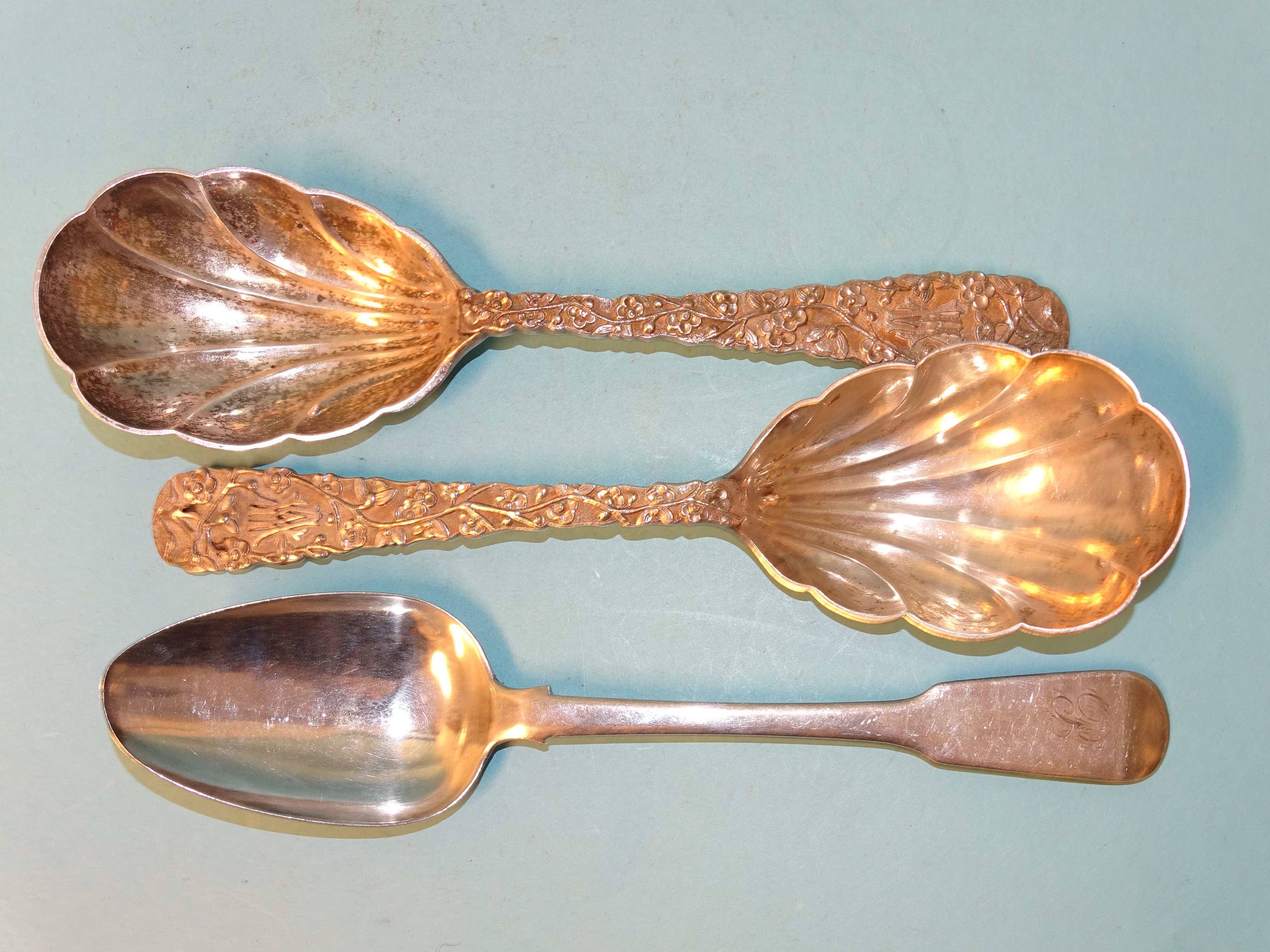 A pair of Oriental serving spoons with prunus-decorated handles and shell bowls, marked 'LW' and a