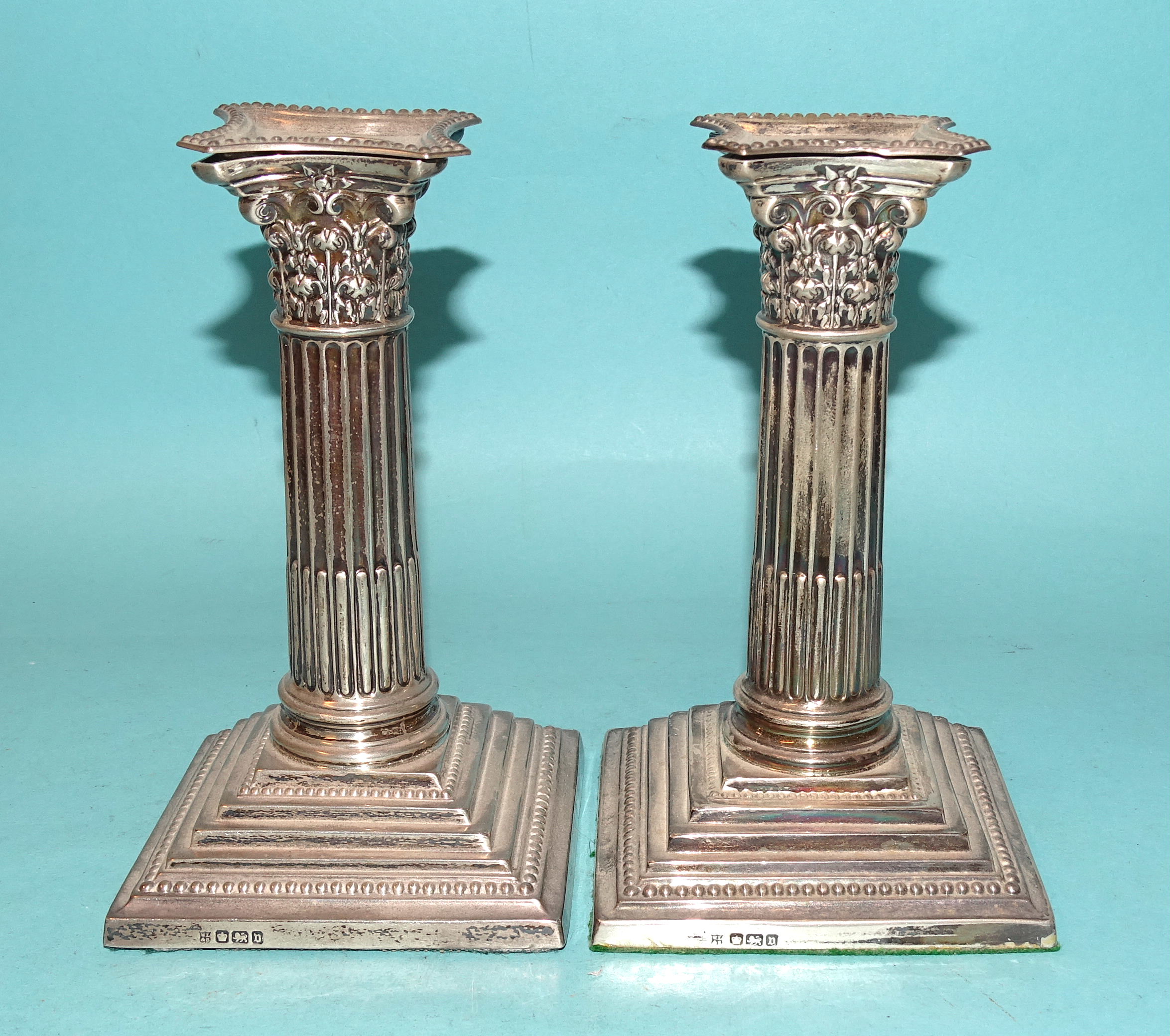 A pair of silver Corinthian column short candlesticks with detachable beaded sconces and loaded