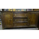 An oak dresser base, the rectangular top above three central drawers flanked by cupboard doors,