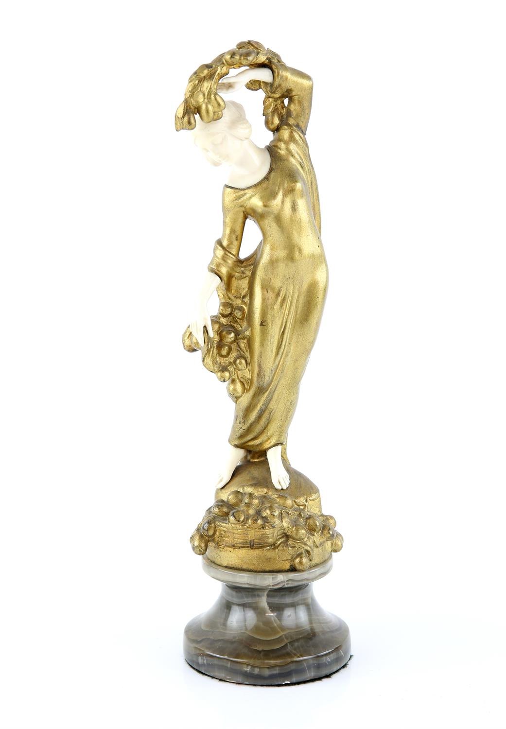 Art Nouveau cast gilt metal and ivoreen figure of a young girl with a basket of fruit at her feet,