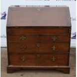 George III oak bureau, the slope enclosing a stepped fitted interior with well and secret drawers