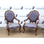 Pair of Victorian walnut salon armchairs, the oval button backs with padded arms and foliate carved