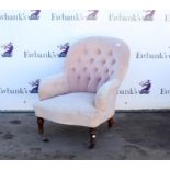 Victorian pink button back fireside armchair, with turned legs and castors