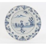 18th century English Delft shallow dish decorated with a figure in a landscape within a foliate