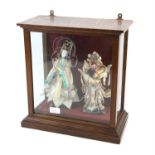 Far Eastern carved and painted wooden puppets and two Japanese dolls in a glass case,