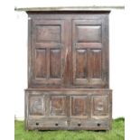 George III oak clothes press, the moulded cornice over a pair of panelled doors enclosing hooks,