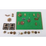 Selection of military badges and a leather dog tag, all on board and a selection of military buttons