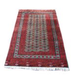 Turkoman rug, the repeating lozenge design on a green field with multiple red and green border,