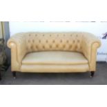 Chesterfield sofa, covered in a cream leatherette, on turned tapering legs and pot castors,