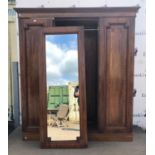Mahogany three door wardrobe, the central mirror flanked by panelled doors on a plinth base,