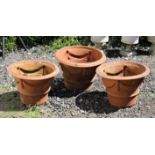 Pair of terracotta garden urns with swag decorated sides, 32 cm high, 46 cm diameter and another