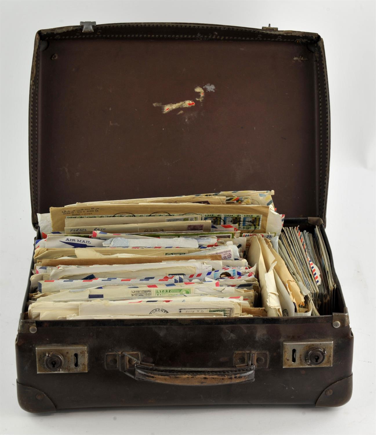 Small brown suitcase containing stamps on envelopes including Australia and Canada.