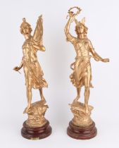 Pair of French metal gilt statues in the form of classical figures on circular plinths,