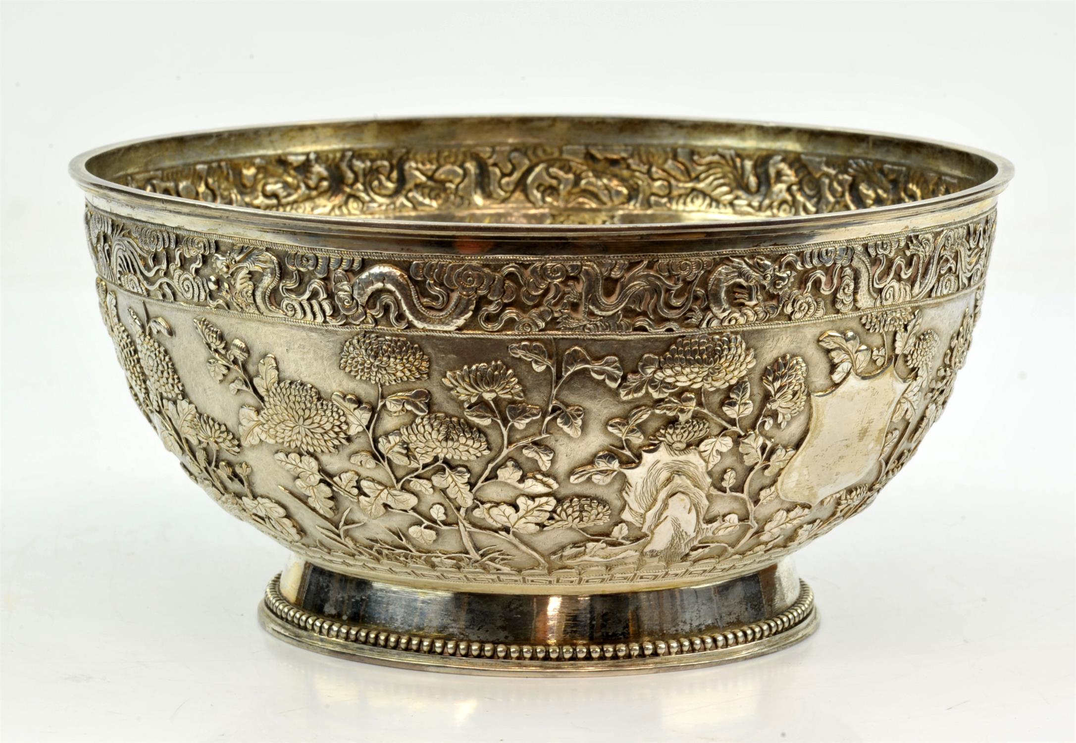 Chinese export silver bowl, embossed with a dragon border above chrysanthemums, maker's mark LH,