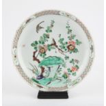 A Chinese famille verte charger Qing dynasty painted with a bird perched on a twig among blossoms,