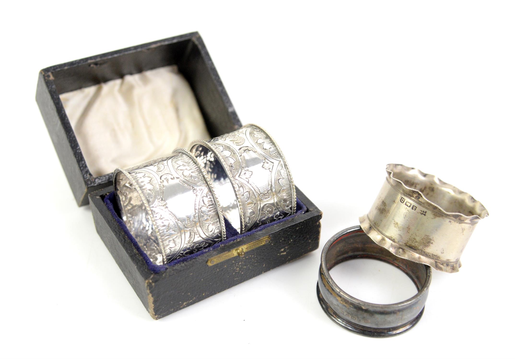 Two silver napkin rings and a cased pair of white metal napkin rings