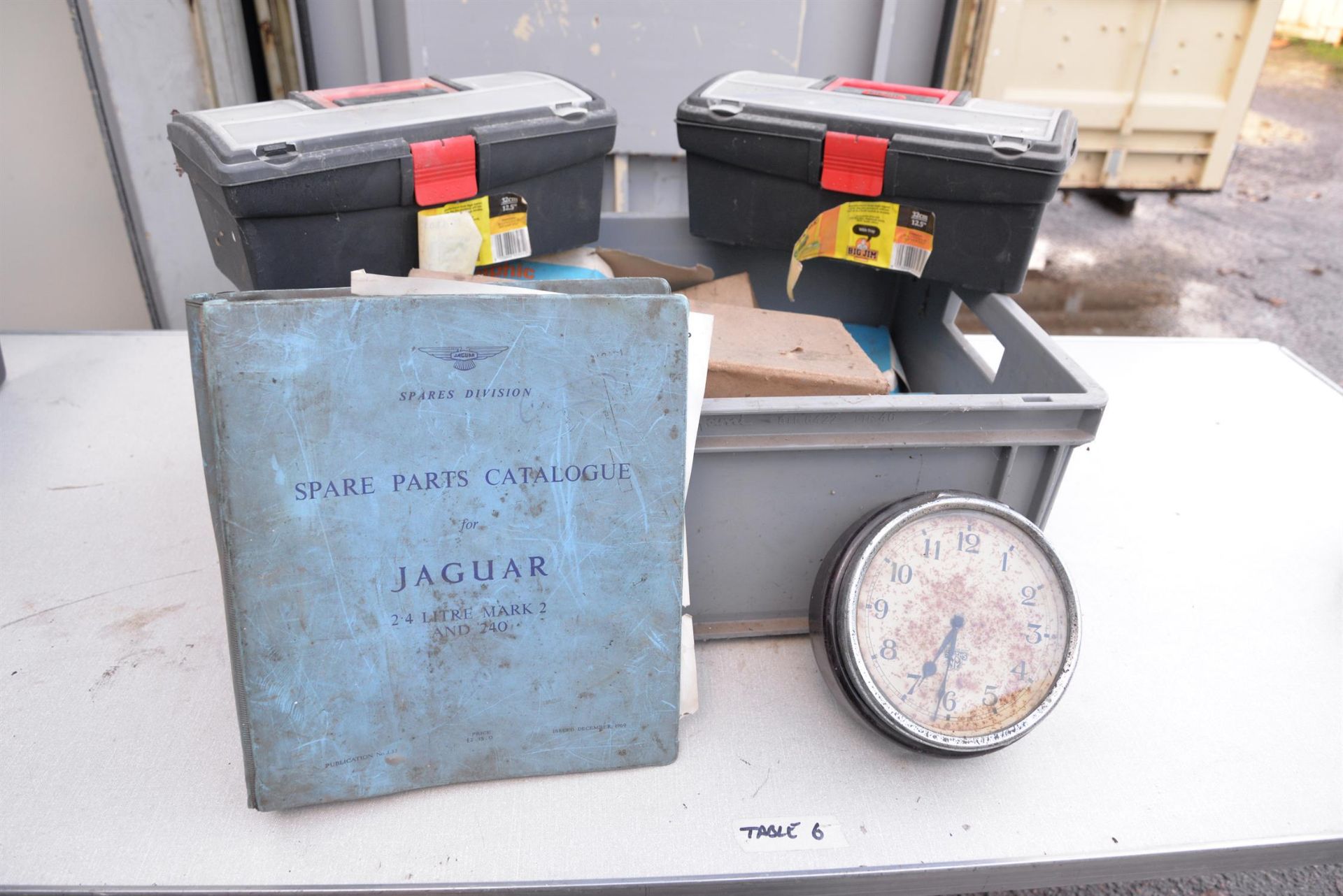 A box of photographic lamps, Lucas spot light, x2 smiths clock, spares catalogue for Jaguar MK2.