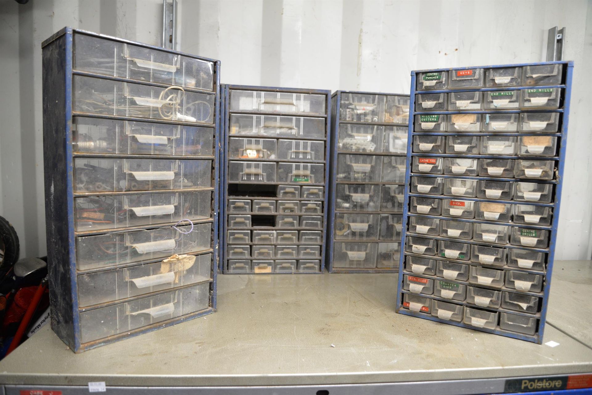 A selection of blue wall drawers for workshop use containing accessories.