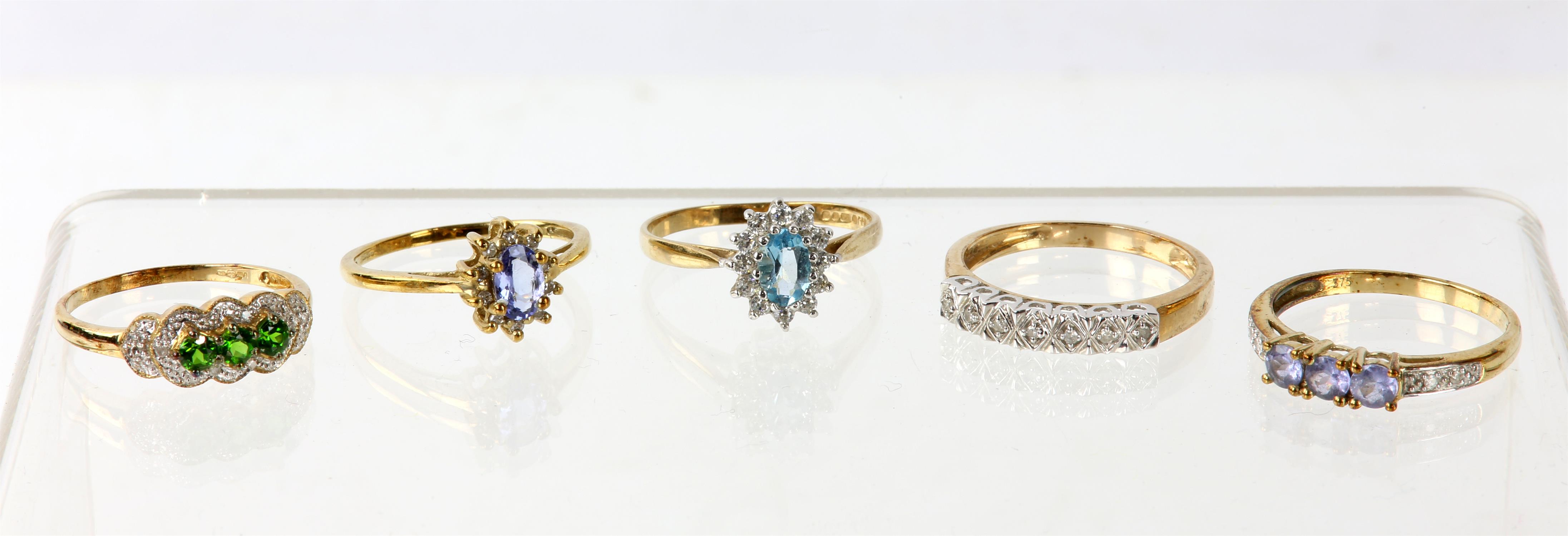 Five dress rings, including a blue topaz cluster ring set with an oval blue topaz and a surround of