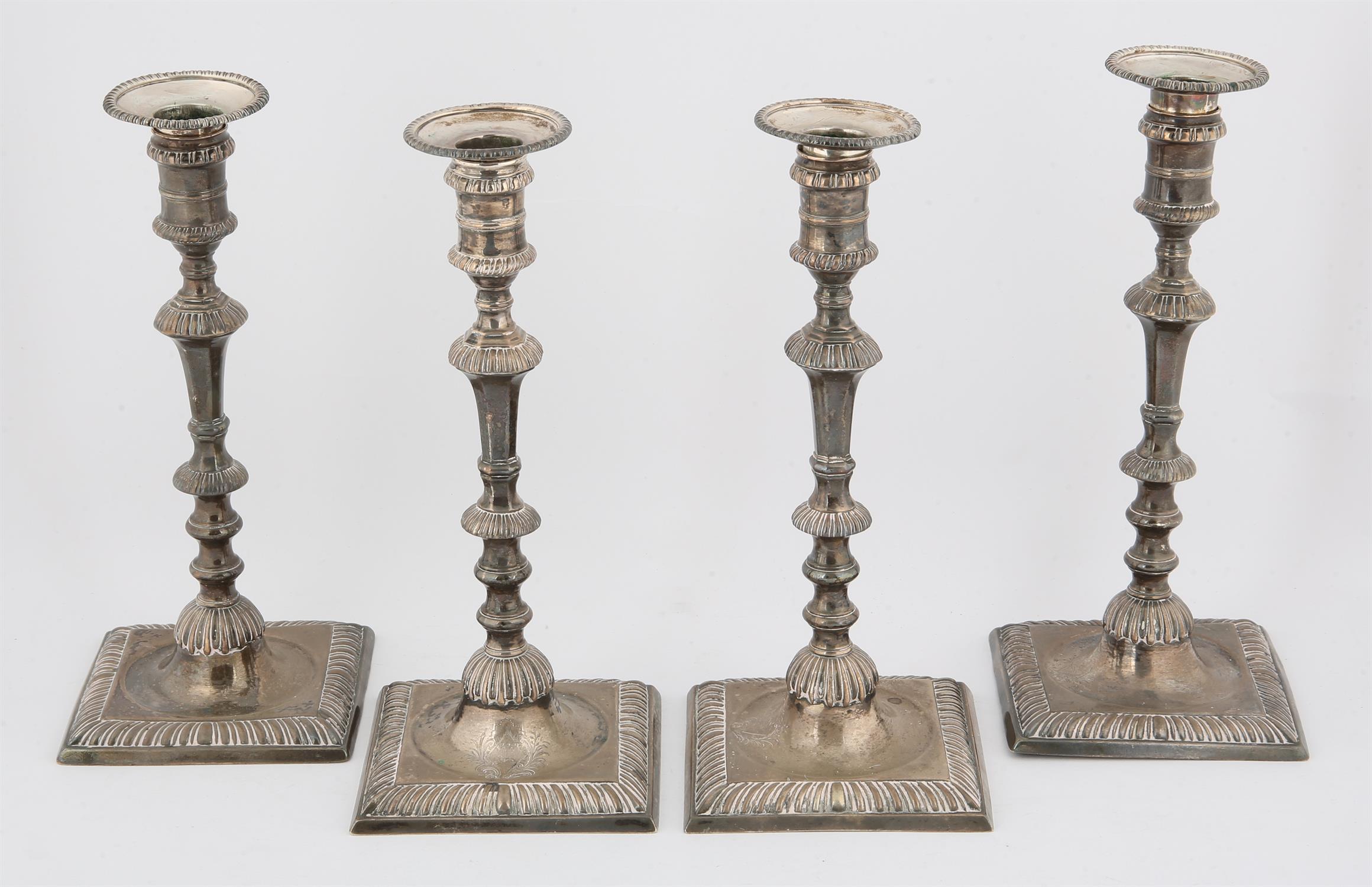 Set of four George III silver candlesticks, the square bases with gadrooned decoration,crested,