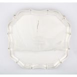 George V silver salver with shaped border supported on four scroll feet, by Barker Brothers Silver