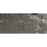 Two wrought iron green painted garden benches, scrolling arms and legs with slatted seats,