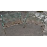 Two wrought iron green painted garden benches, scrolling arms and legs with slatted seats,