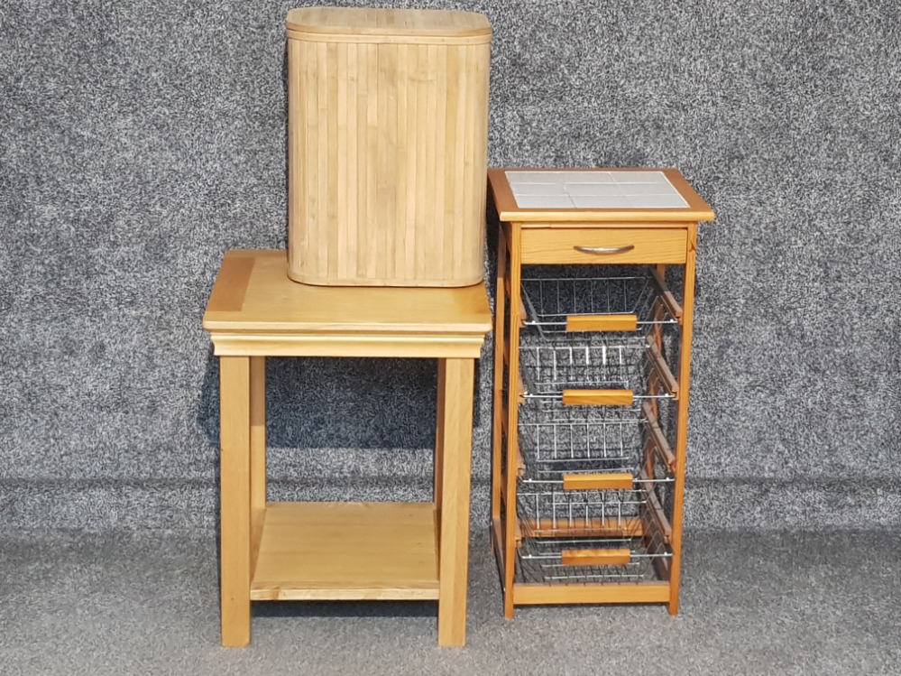 Tile topped kitchen storage unit together with light oak side tabel and wooden laundry bin