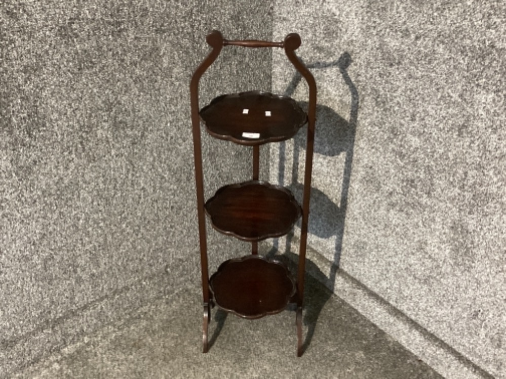 A carved mahogany three tier folding cake stand