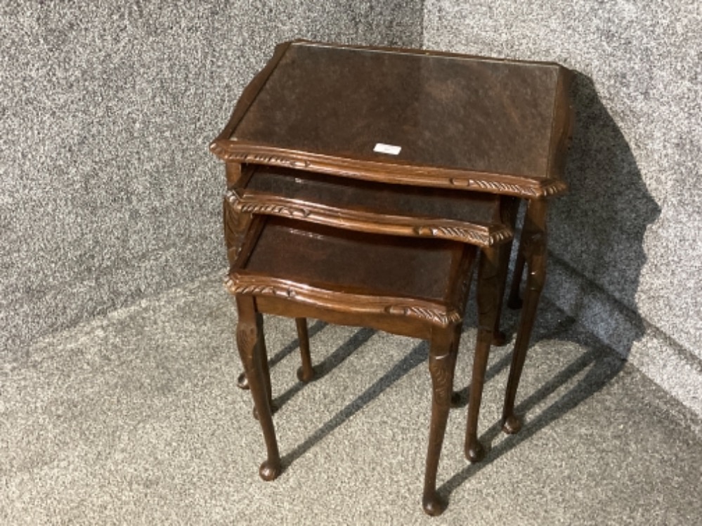 A carved mahogany nest of tables with glass tops