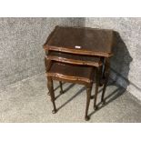 A carved mahogany nest of tables with glass tops