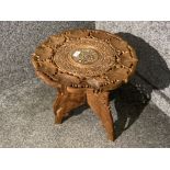 A carved Indian wood tripod table with folding stand