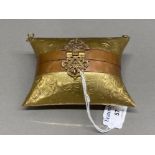 A brass purse in the form of a pillow, with intricate clasp
